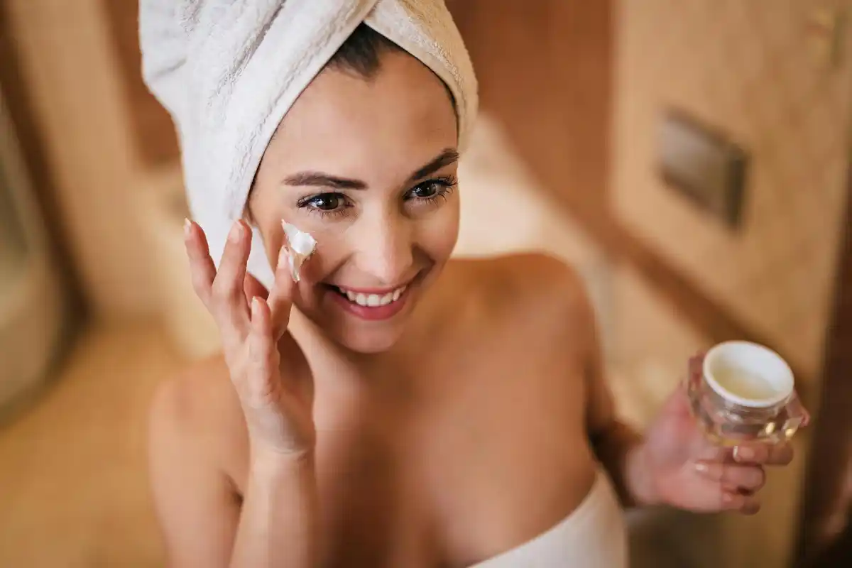 Czech woman applying butter on her face, close up, morning light