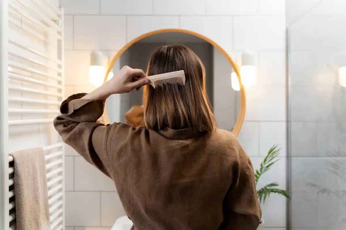 woman applying olive oil hair mask home bathroom mirror