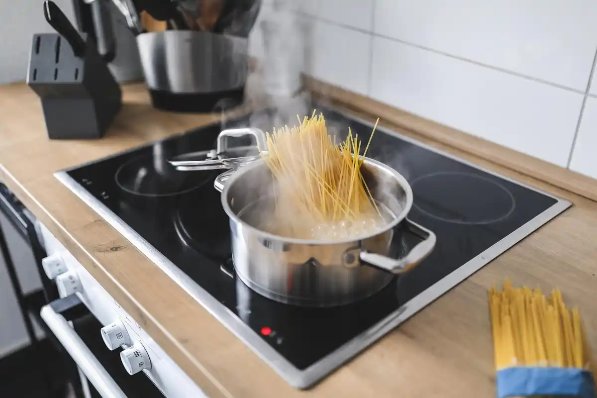 boiling water pouring over pasta in a pot