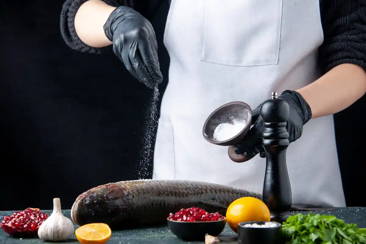 chef adding spices to pot close up