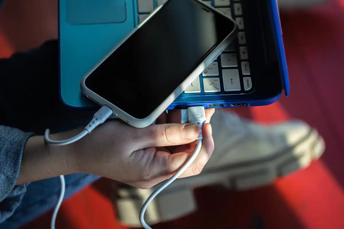 damaged smartphone battery overheating, close-up, hand, white cable