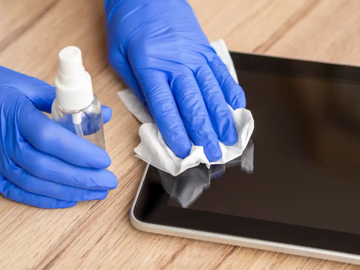 person cleaning tablet screen with rubber glove