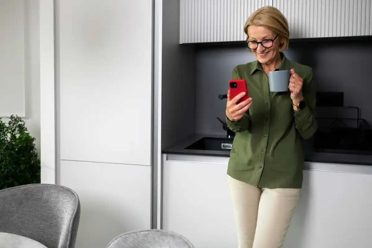 Senior woman setting up her smartphone, cheerful, modern apartment Prague