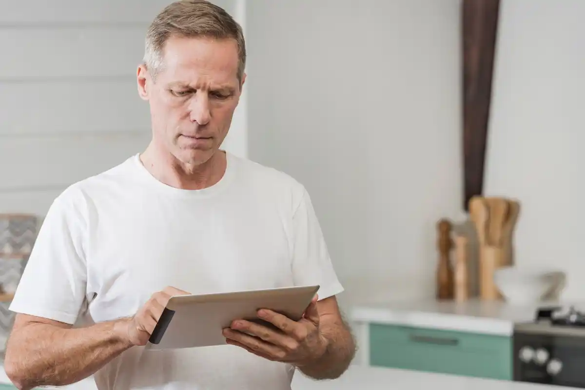 elderly man reading news on tablet at home Czech