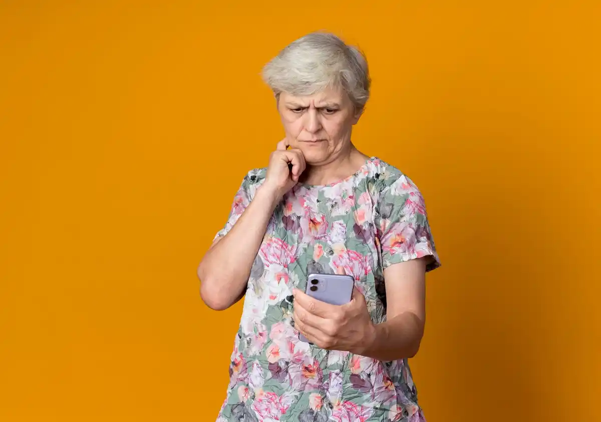 elderly woman worried looking at smartphone payment app