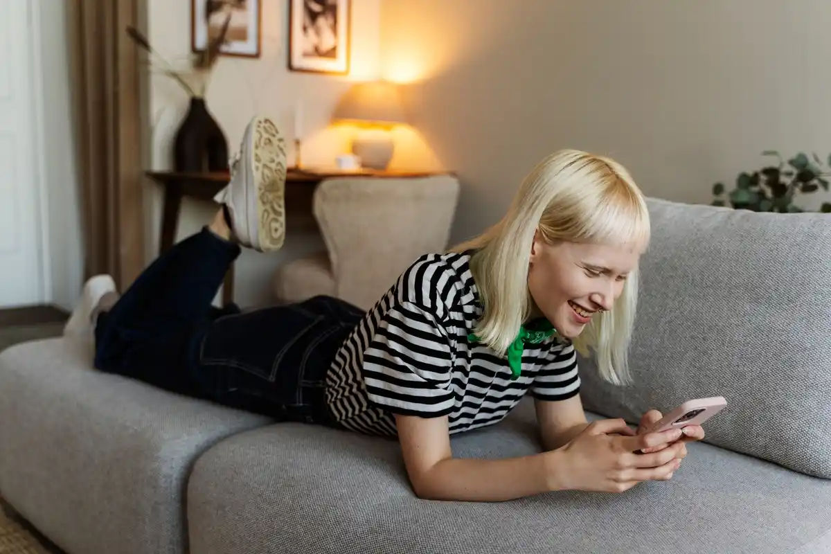 young Czech woman scrolling smartphone on couch tired