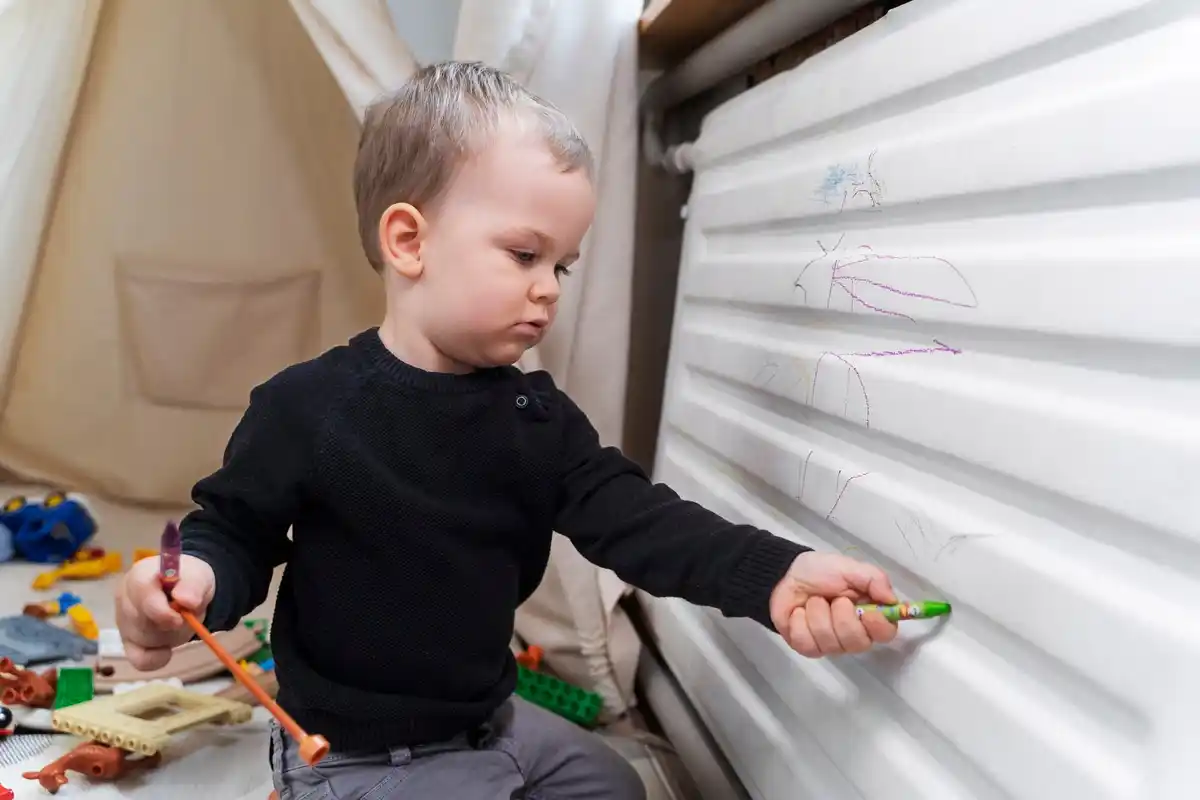 child playing with colorful plasticine at home window