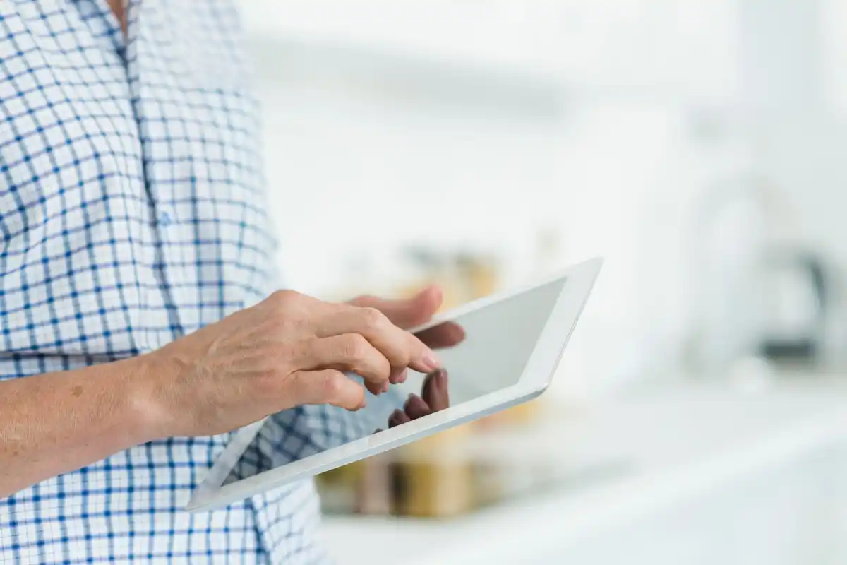 senior using tablet for online shopping at kitchen