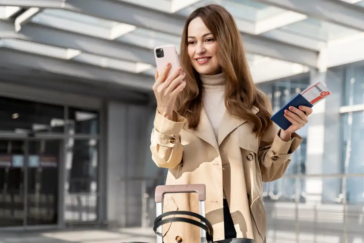 happy traveler with phone and suitcase at airport, checking low flight prices, czech, early morning