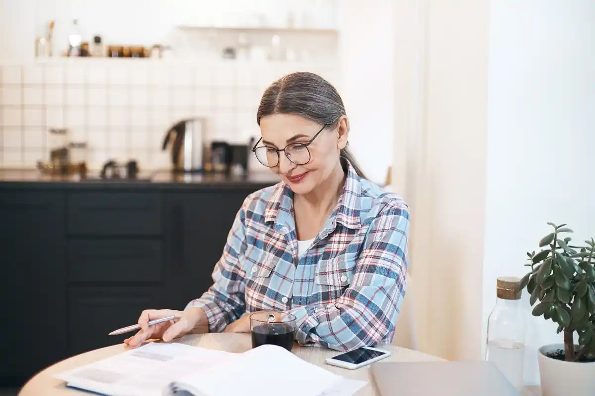 czech senior woman budgeting money notebook kitchen