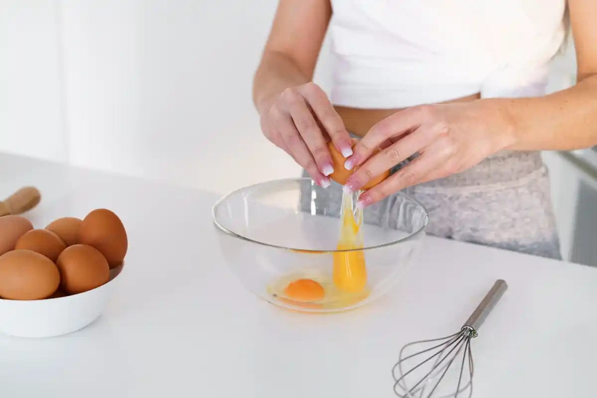 whipped egg whites in glass bowl close up with kitchen mixer