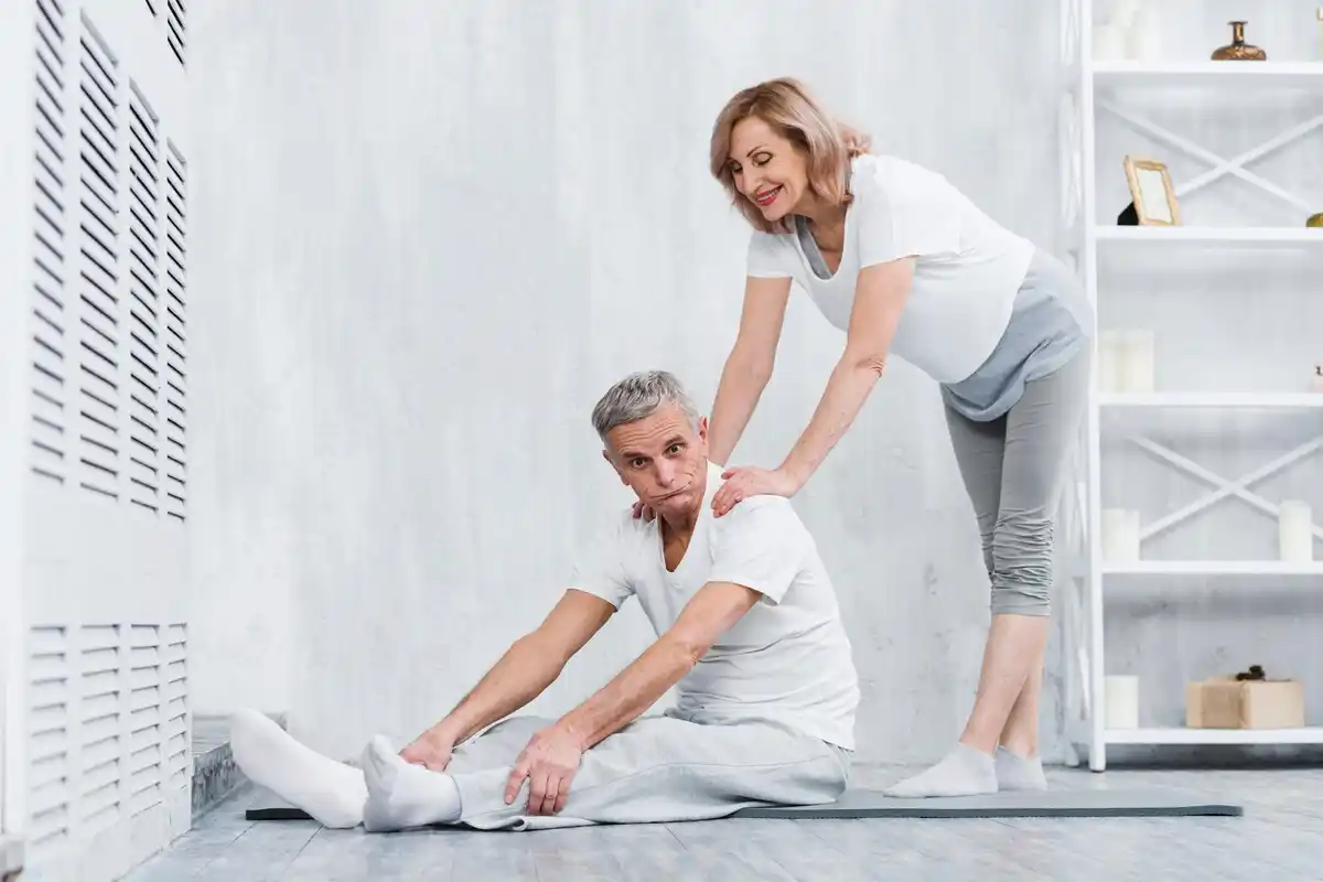 physiotherapist helping middle-aged person stretching