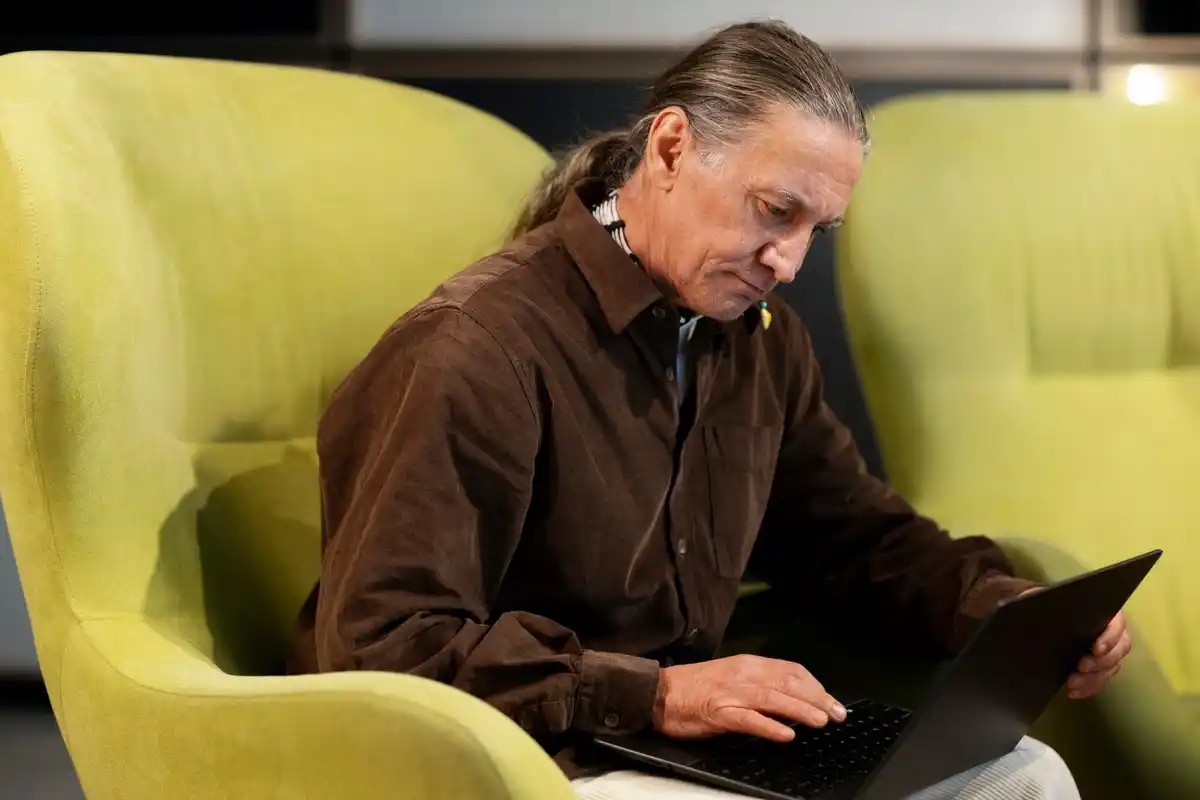 older man studying coding with laptop in cafe prague